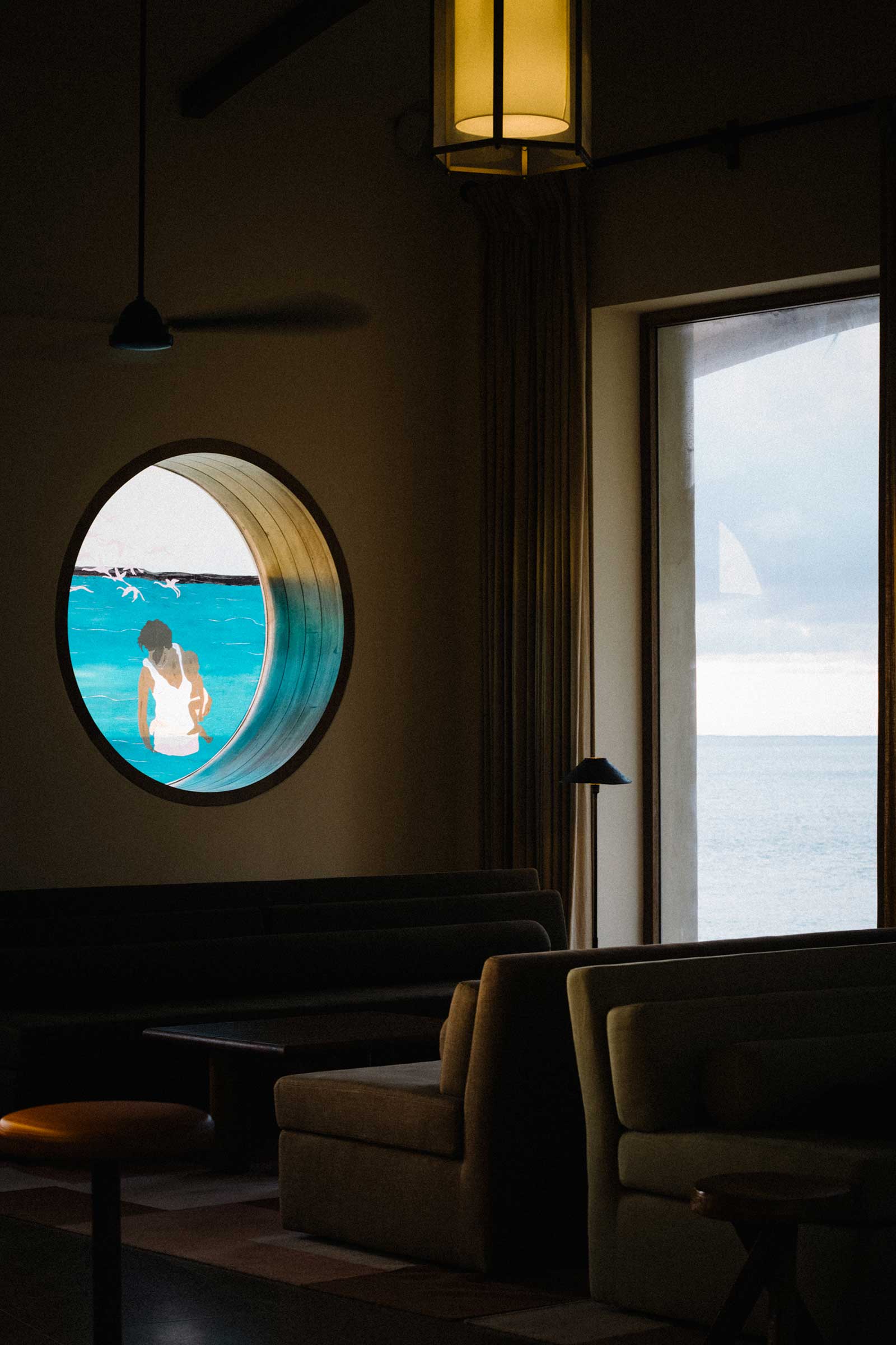Window with artwork in vinyl applied in the Main Terrace restaurant, with seats and ocean view out large window at Kisawa Sanctuary, Benguerra Island, Bazaruto Archipelago, Mozambique
